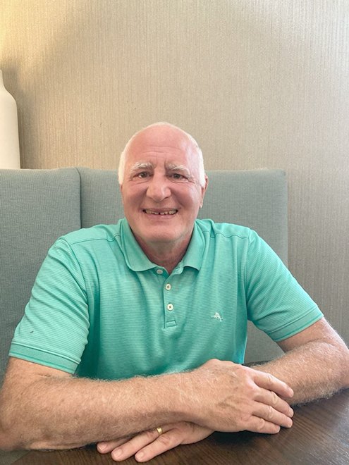 Resident Michael Pinto seated in a teal polo shirt